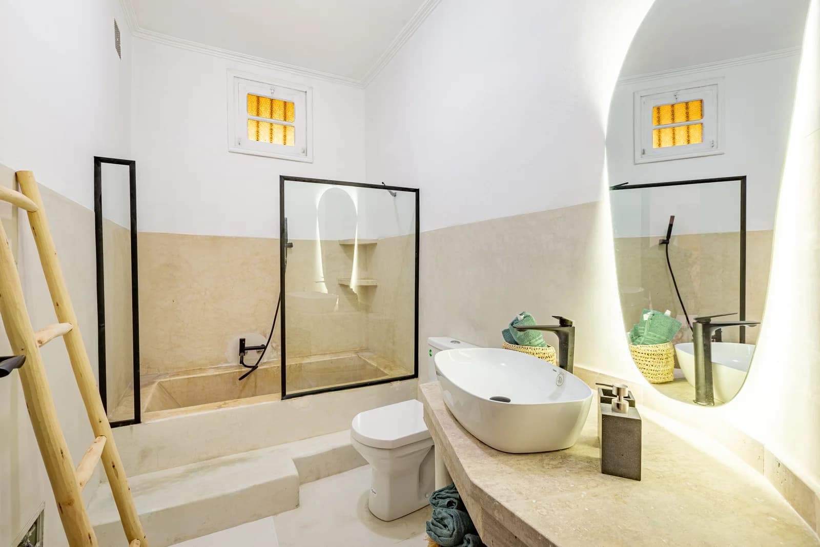 Travertine wet-room bathroom with curved mirror and timber ladder