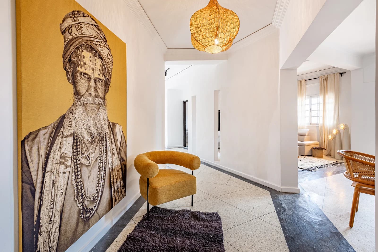 Hallway anchored by oversized maharaja portrait and mustard armchair
