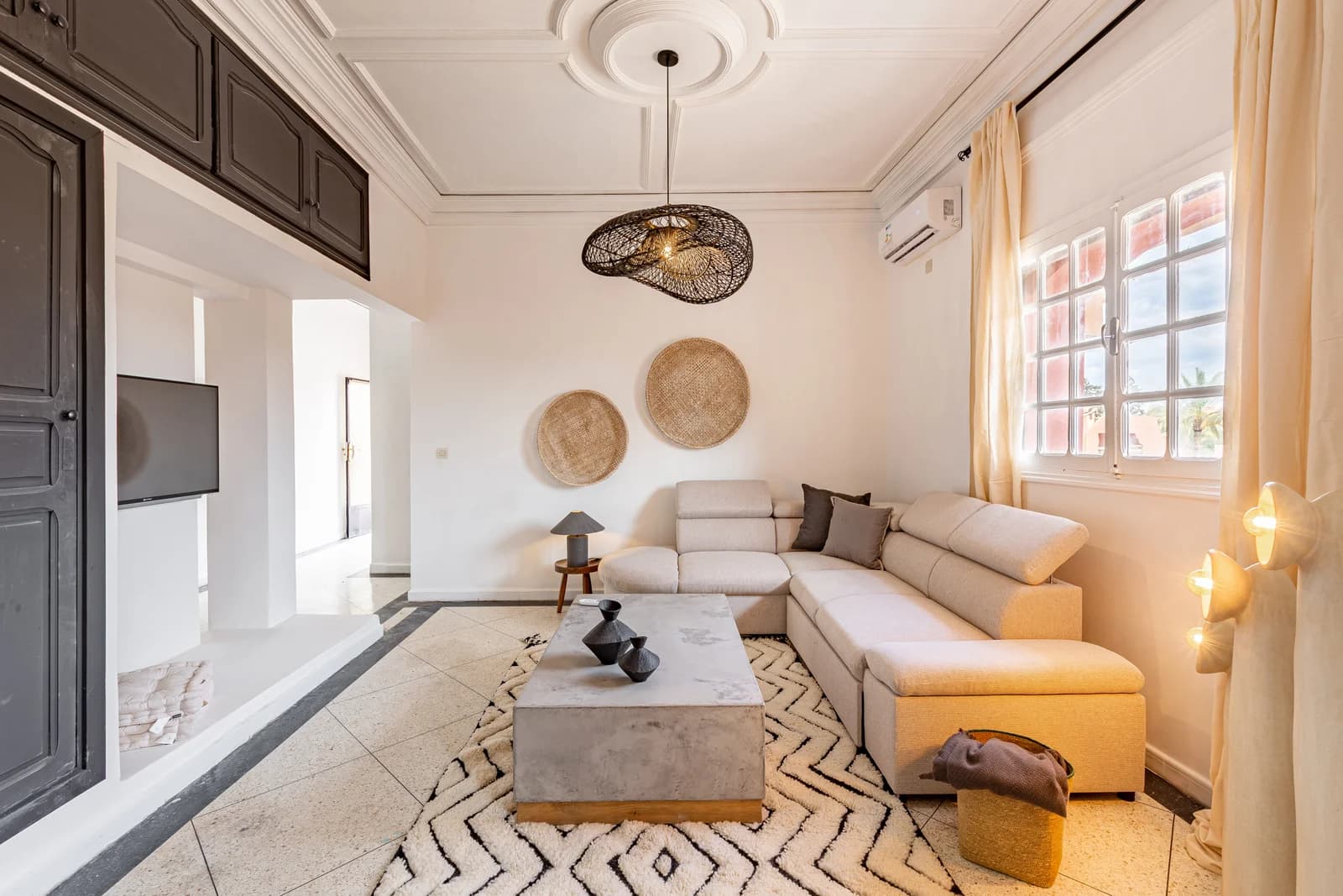 Sculpted ceiling, sectional sofa and graphic Berber rug in soft daylight