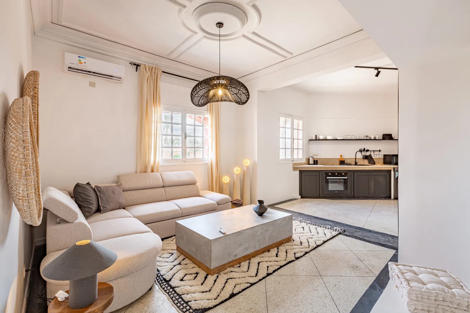 Open living and kitchen with rattan pendant and cream sectional sofa