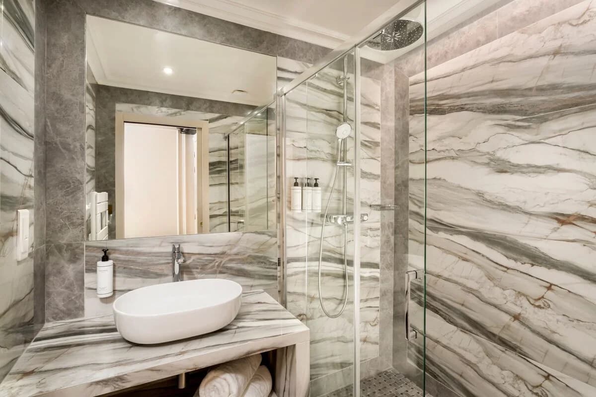 Onyx-veined marble bathroom with vessel sink and walk-in shower