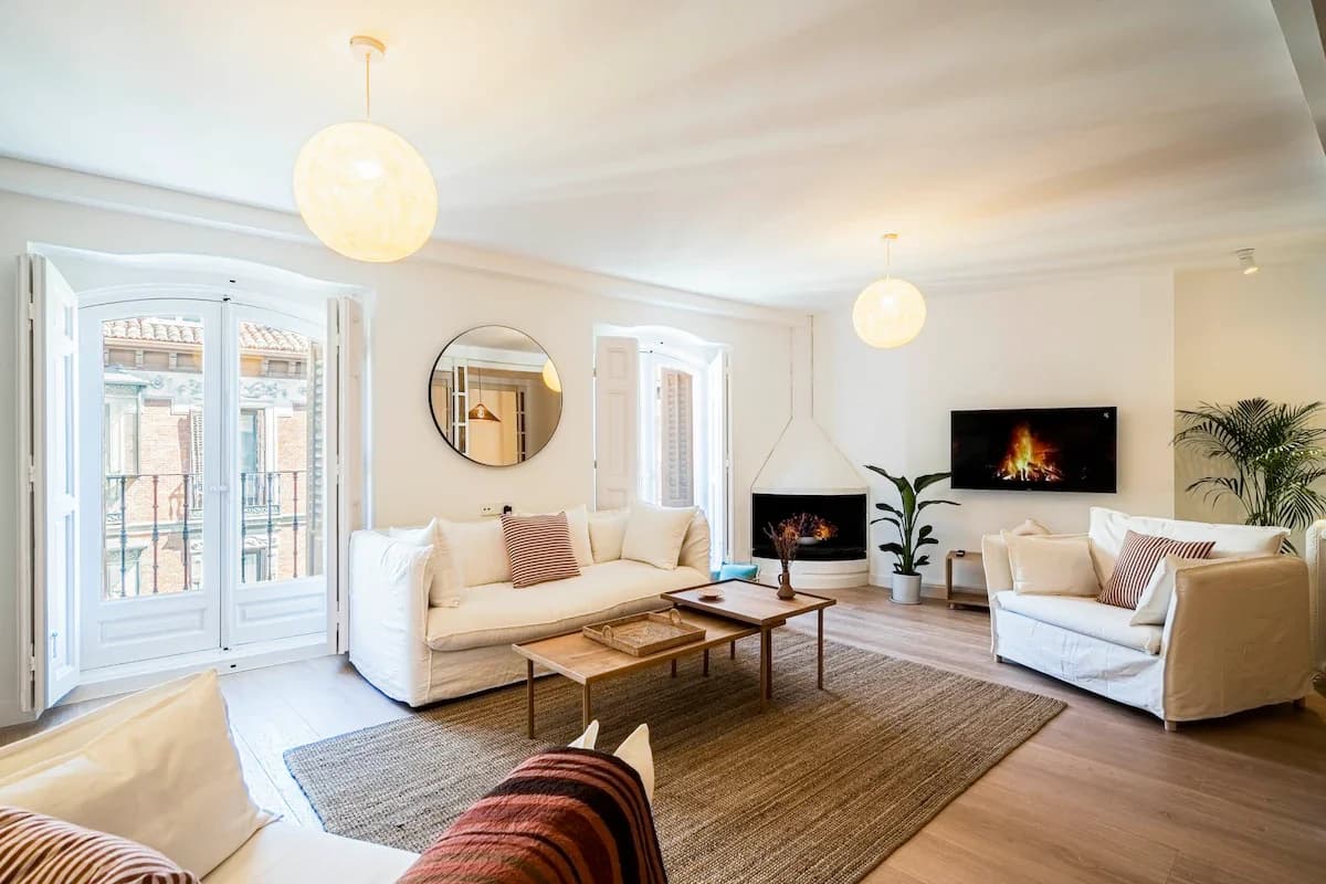 Wide living room with arched balcony doors, fireplace and twin globe pendants