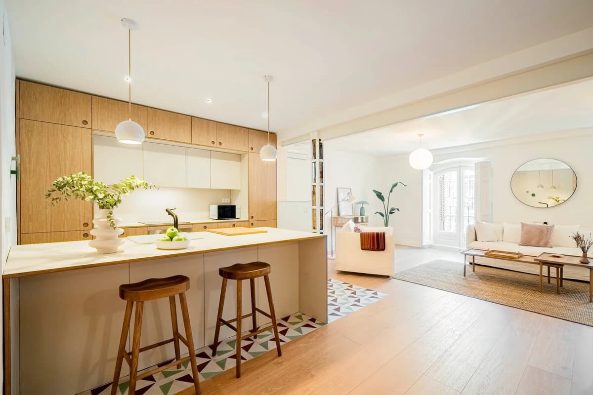 Oak kitchen island with patterned encaustic tile floor opening to lounge