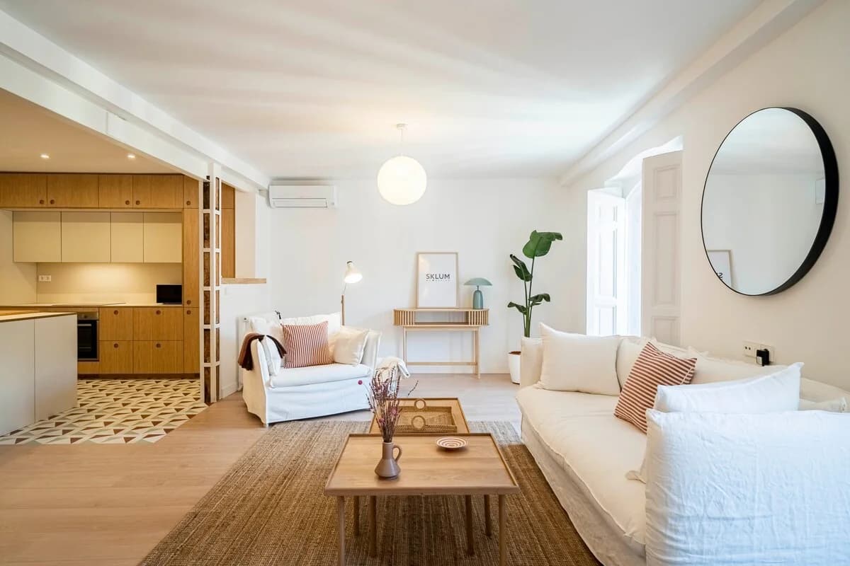 White slipcover sofas, jute rug and circular black mirror in serene lounge