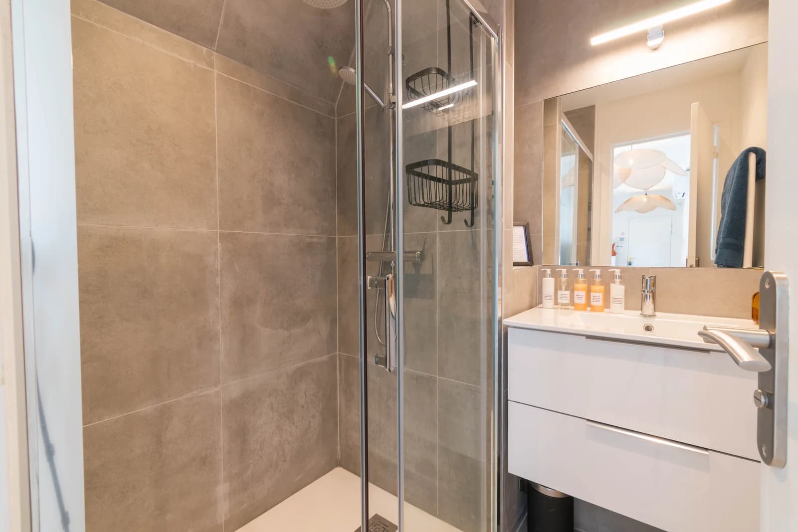 Compact bathroom with grey stone shower and white floating vanity