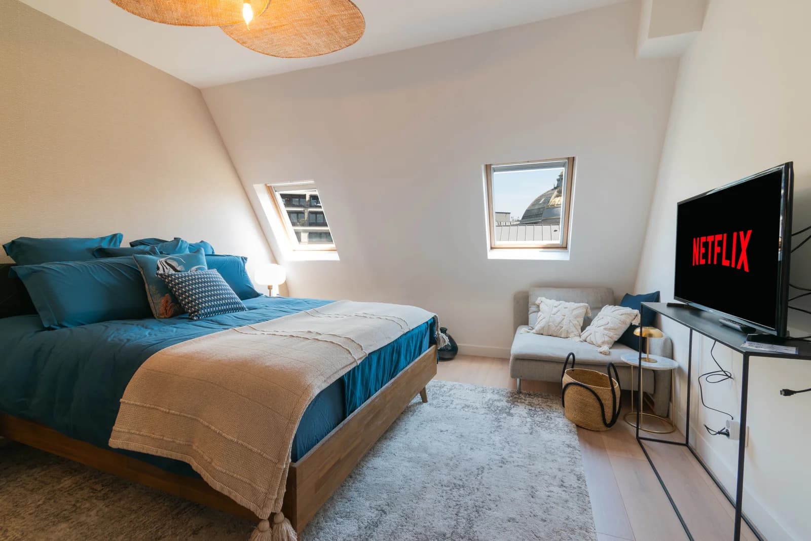 Blue-linen bedroom with arched window framing the Garnier Opera dome