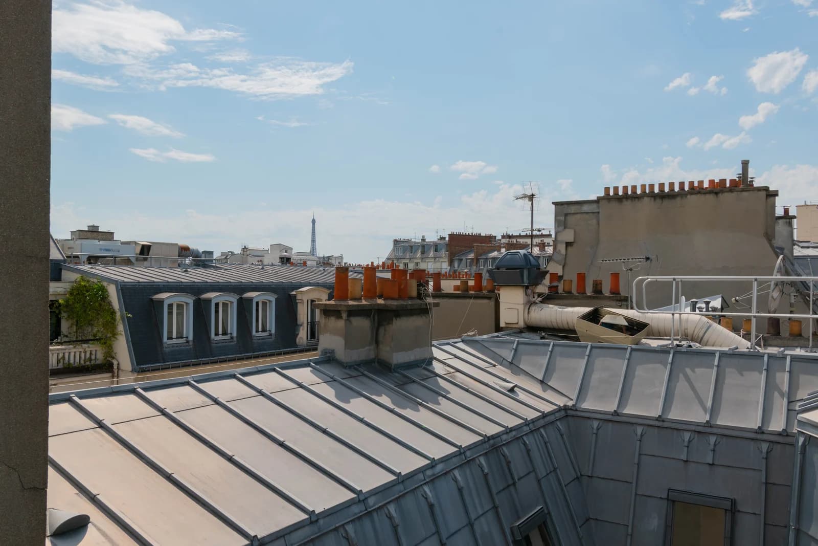 Zinc rooftops of Paris stretch toward the Eiffel Tower in summer light