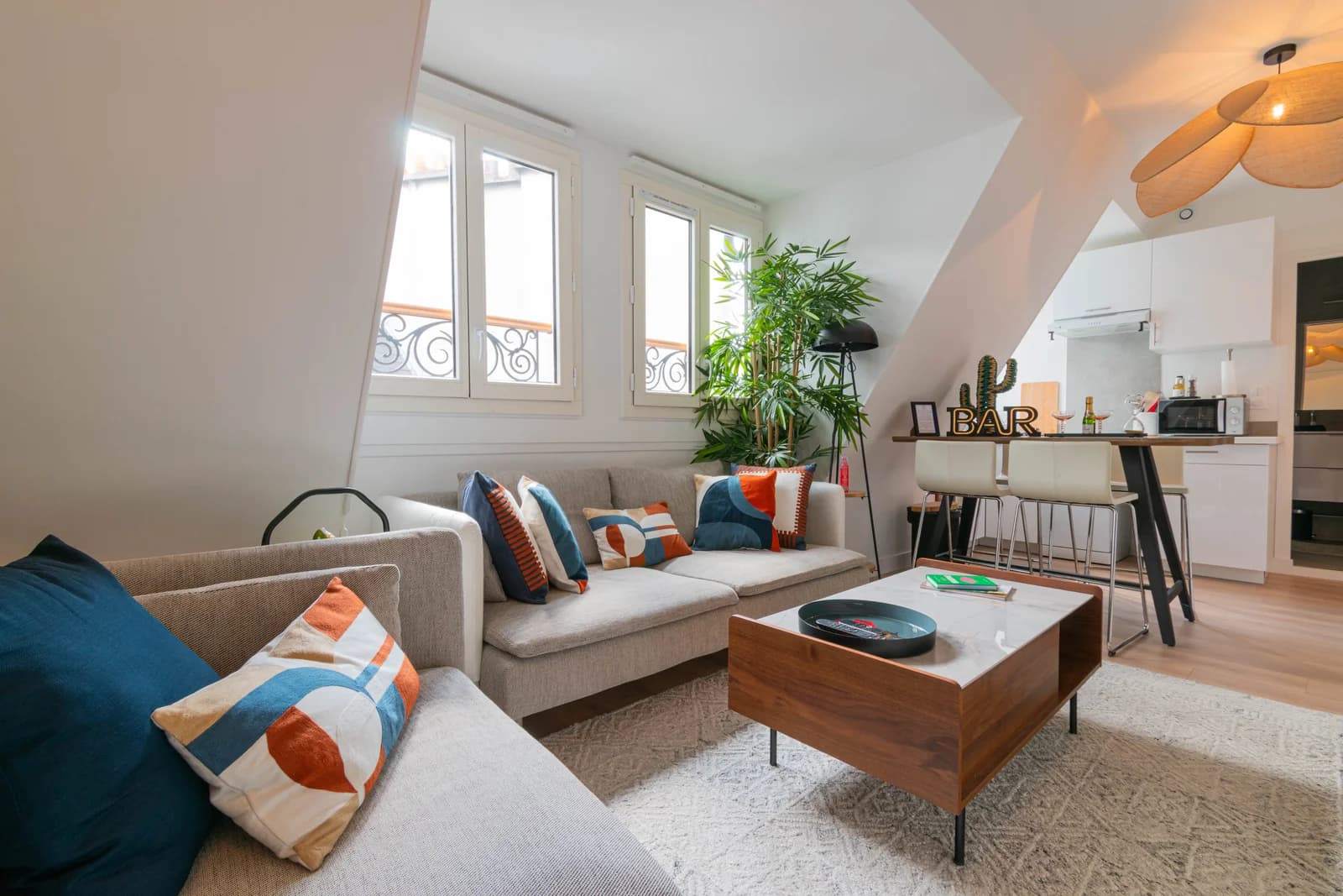Sunlit attic living room with corner sofa and bar-counter view to kitchen