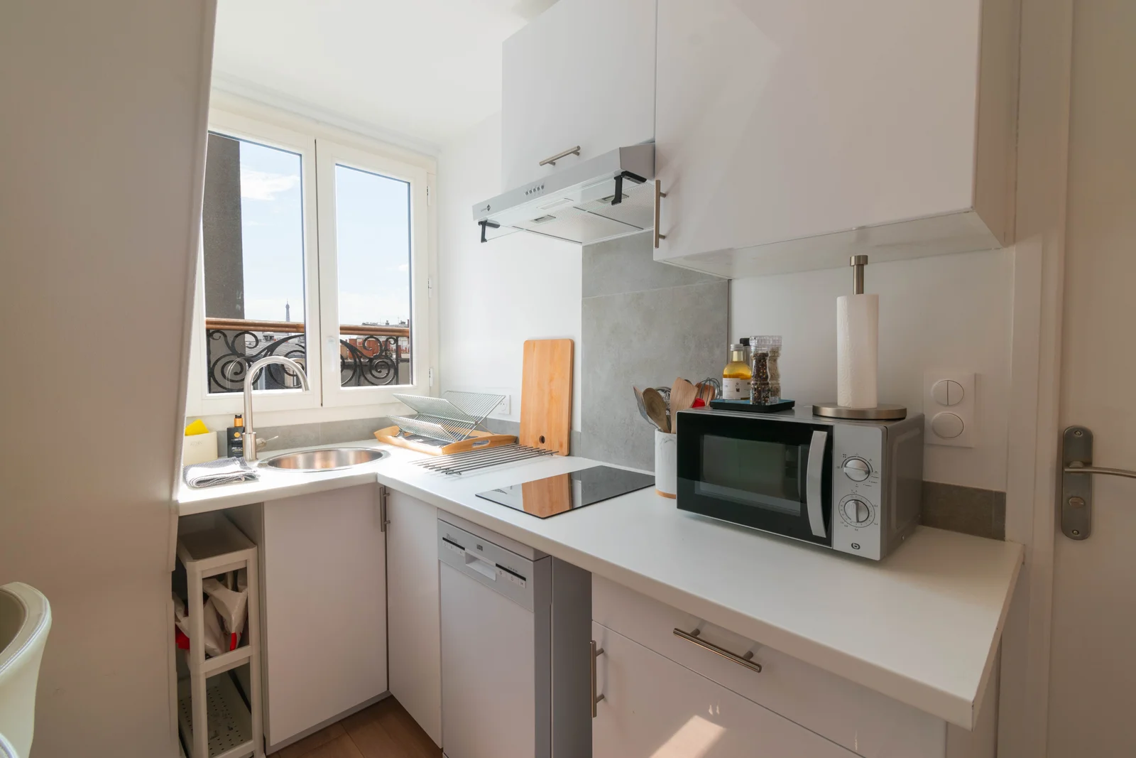 Compact white kitchen with skyline glimpse over wrought-iron Juliet balcony