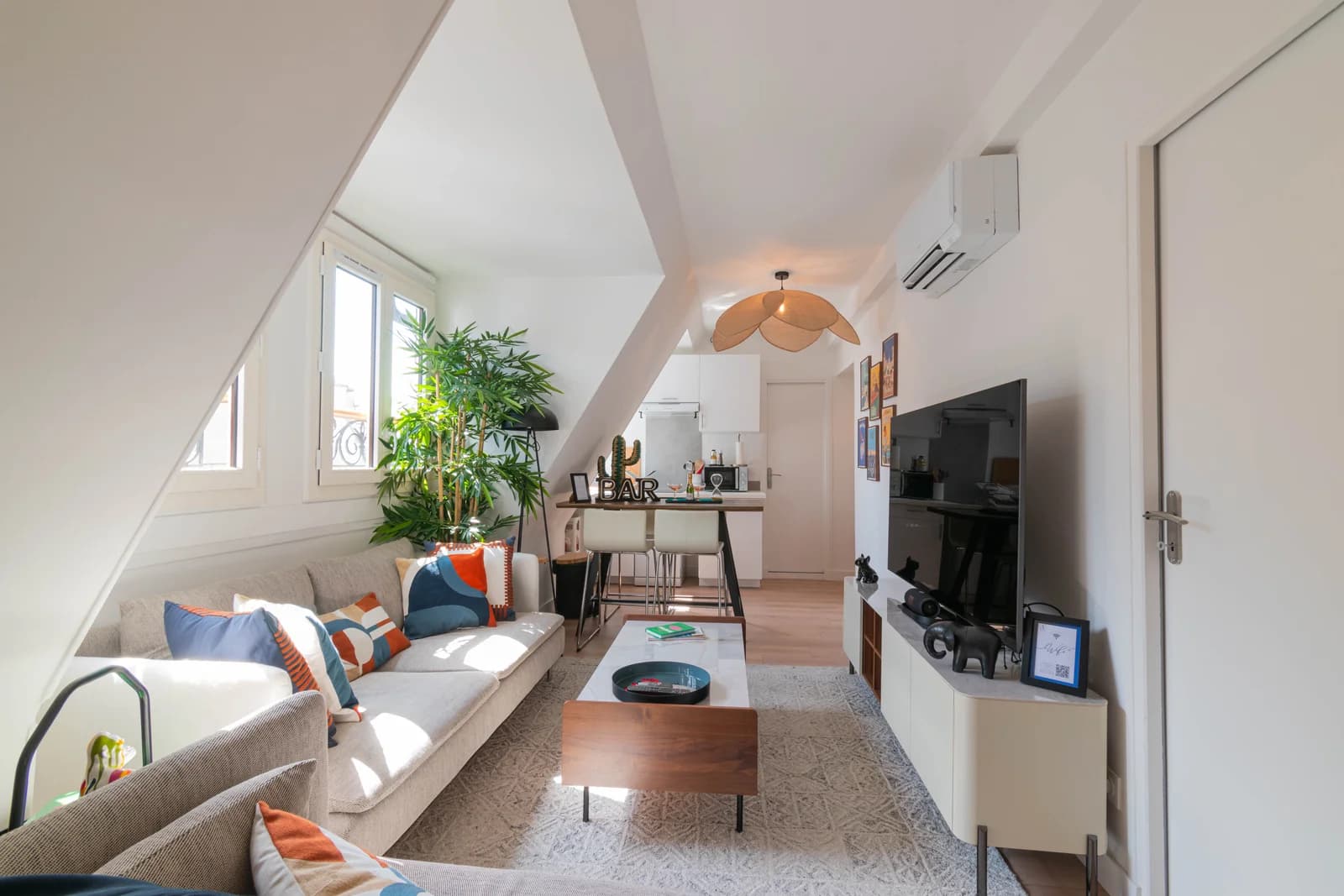 Long view of attic living room into kitchen under sloped white ceiling