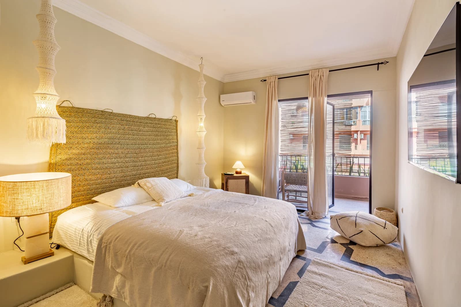 Master bedroom with woven headboard, balcony access and warm light