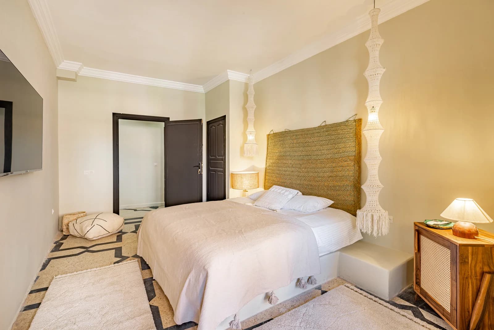 Bedroom with woven hanging headboard, geometric floor and twin lamps