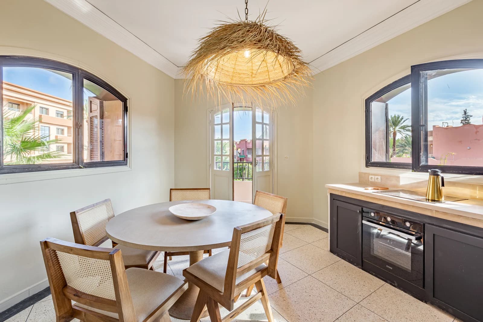 Bright dining-kitchen with arched balcony doors and rattan pendant