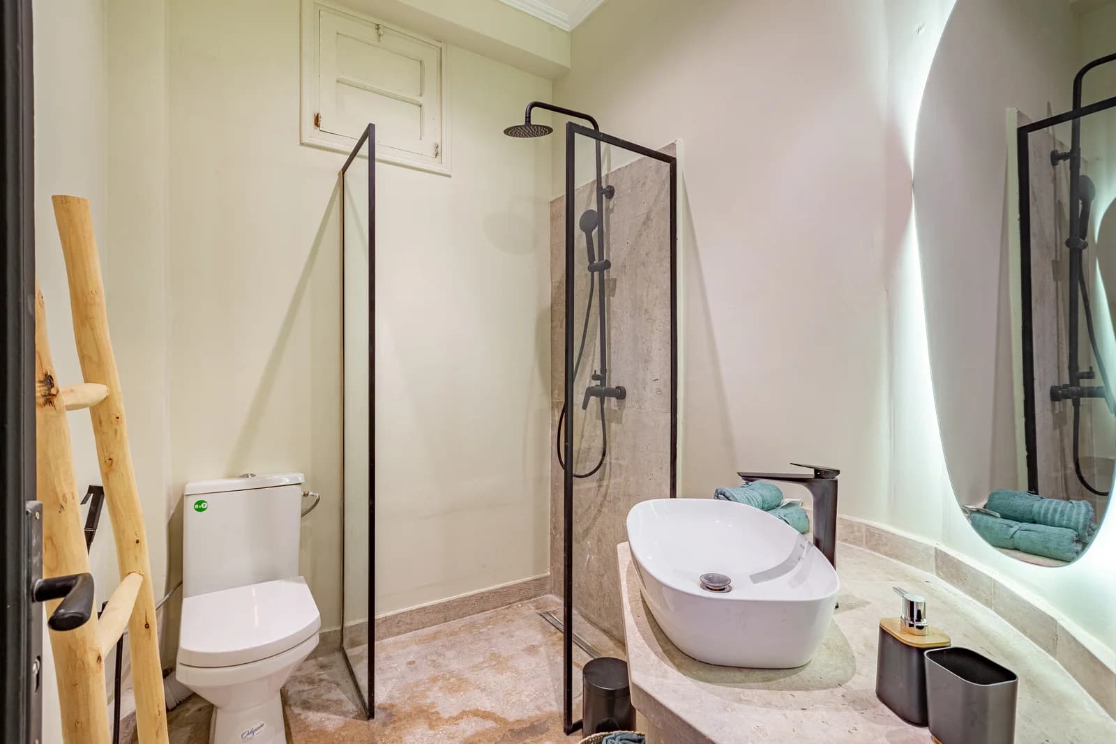 Walk-in shower bathroom with travertine floor and curved black mirror