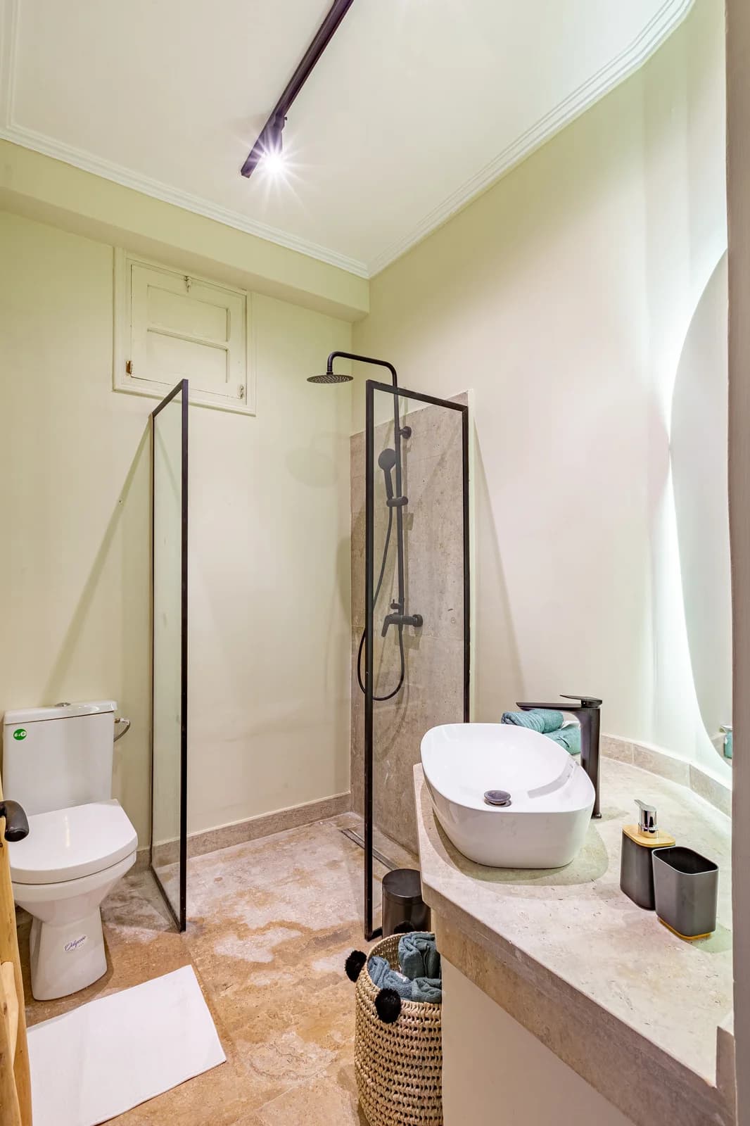 Compact shower bathroom with light green walls and stone vanity
