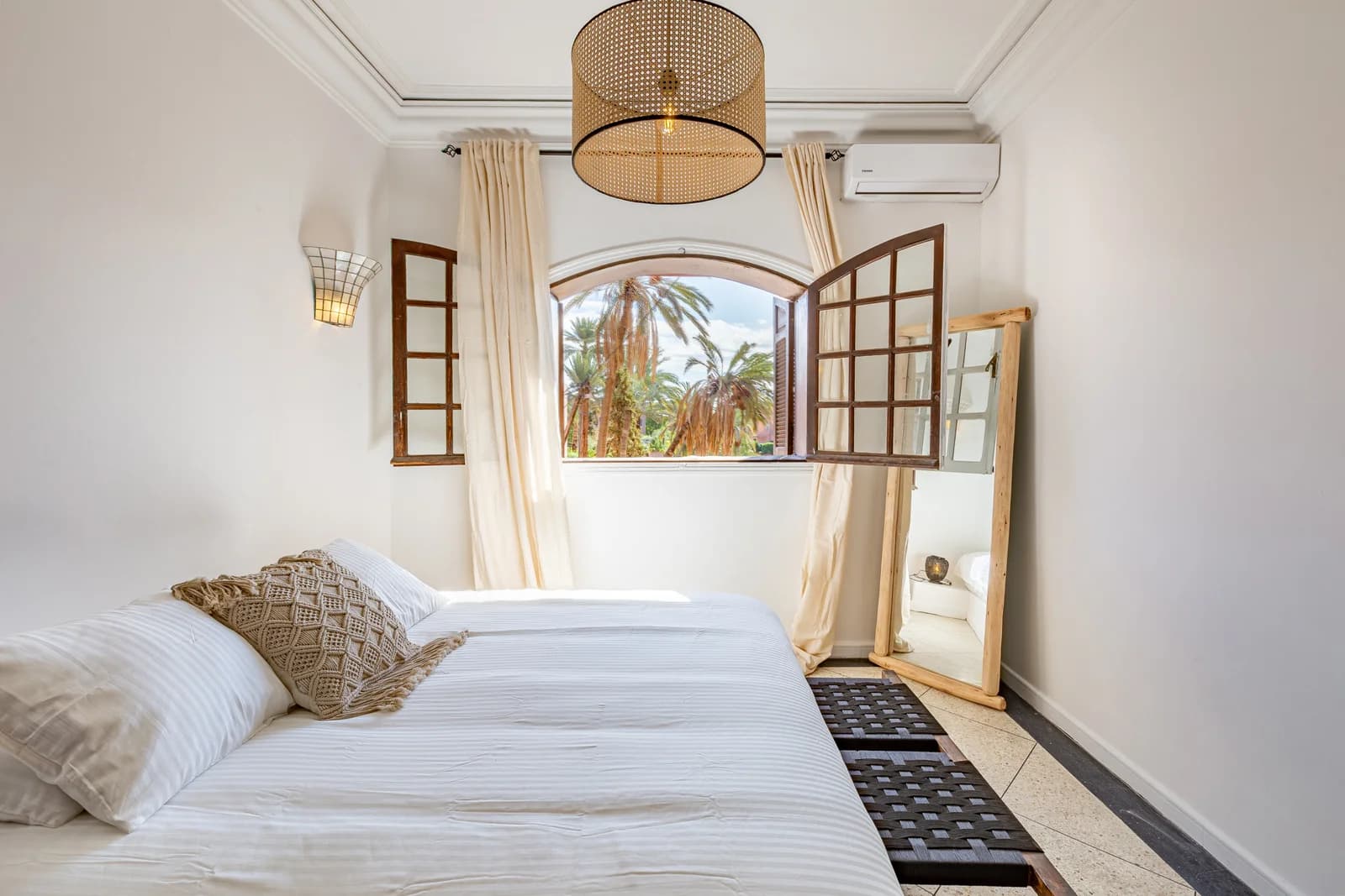 Calm bedroom with woven pendant, arched window and beige linens