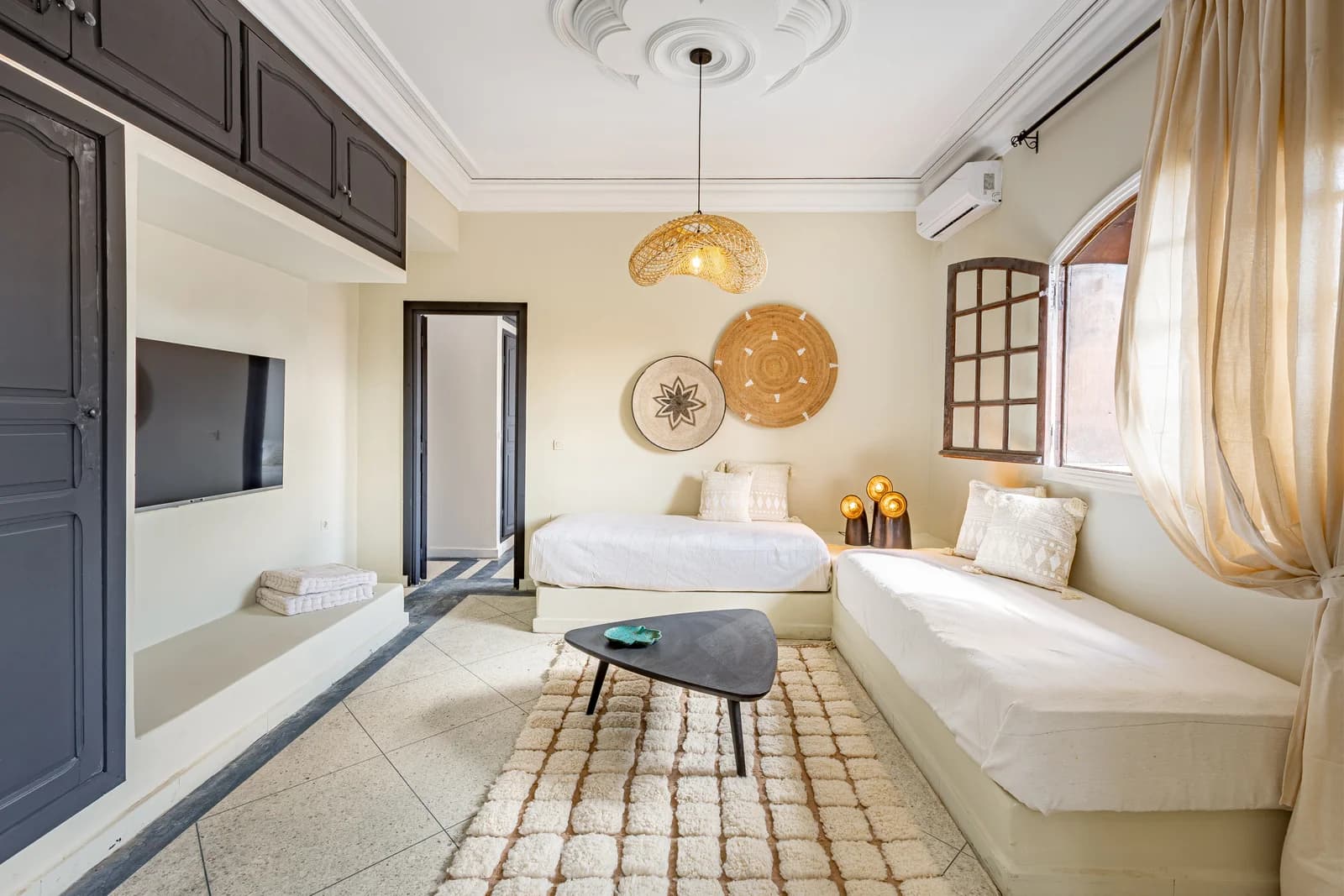 Twin bedroom with woven wall art, plaster ceiling rose and arched window