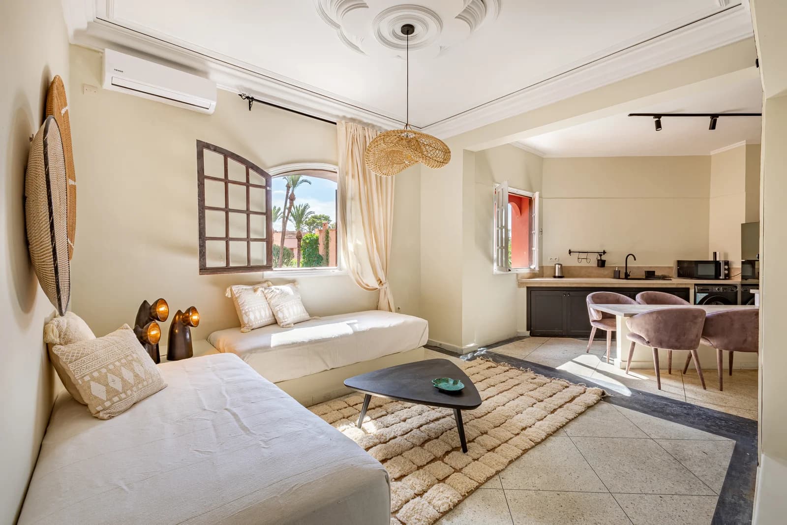 Living room opening into kitchen with arched window and palm view