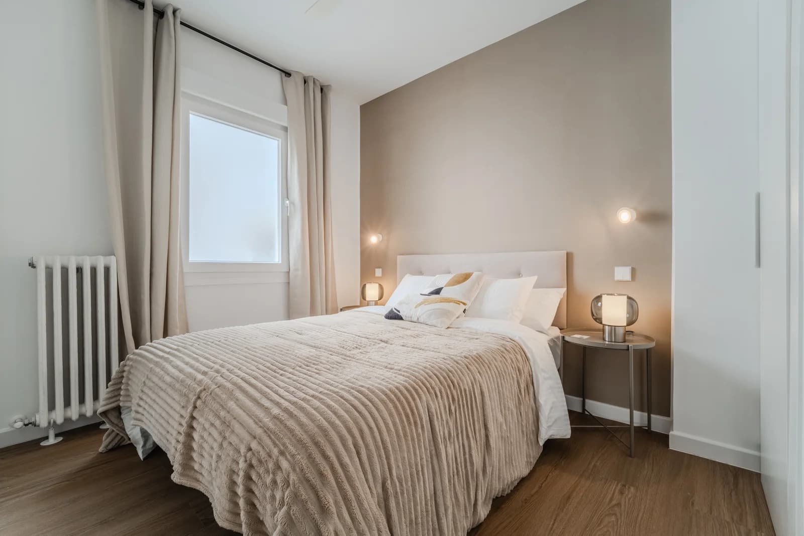 Quiet bedroom with cast-iron radiator, sheer curtains and accent wall