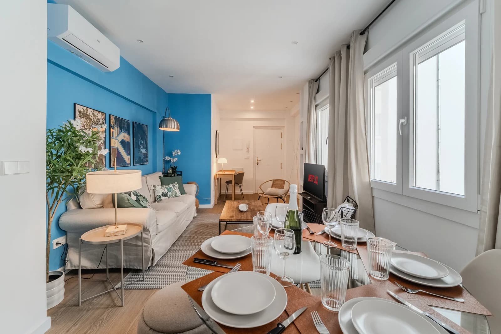 Living view across set dining table toward blue-walled lounge