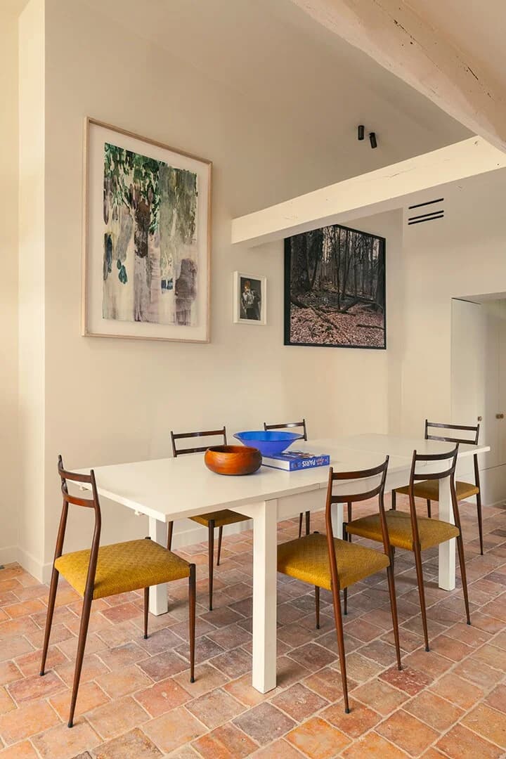 Crisp white dining table with mid-century chairs on terracotta tile