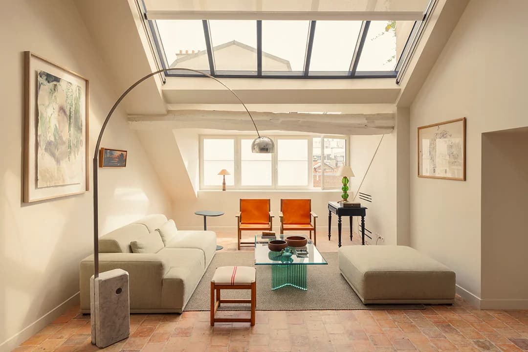 Atelier living room under skylight with arc lamp, leather chairs and beams