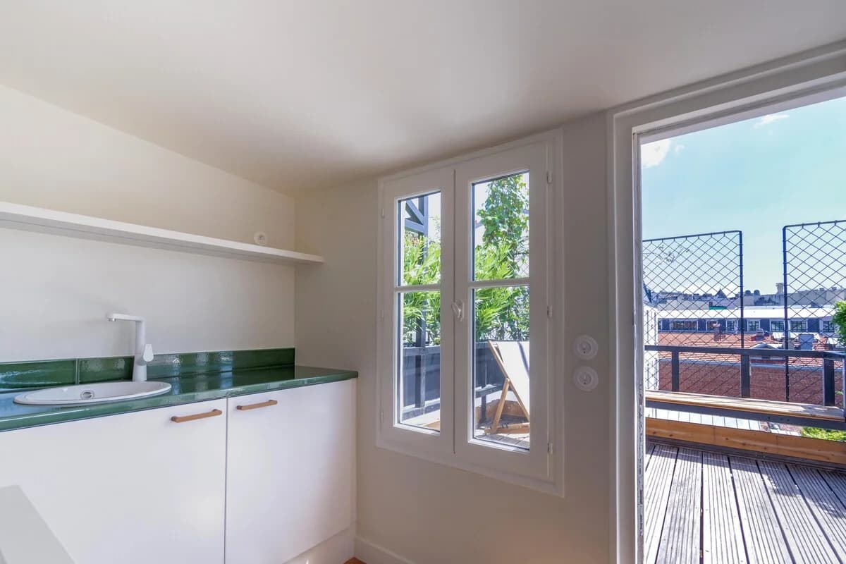 Galley kitchen opening onto rooftop terrace through tall casement door