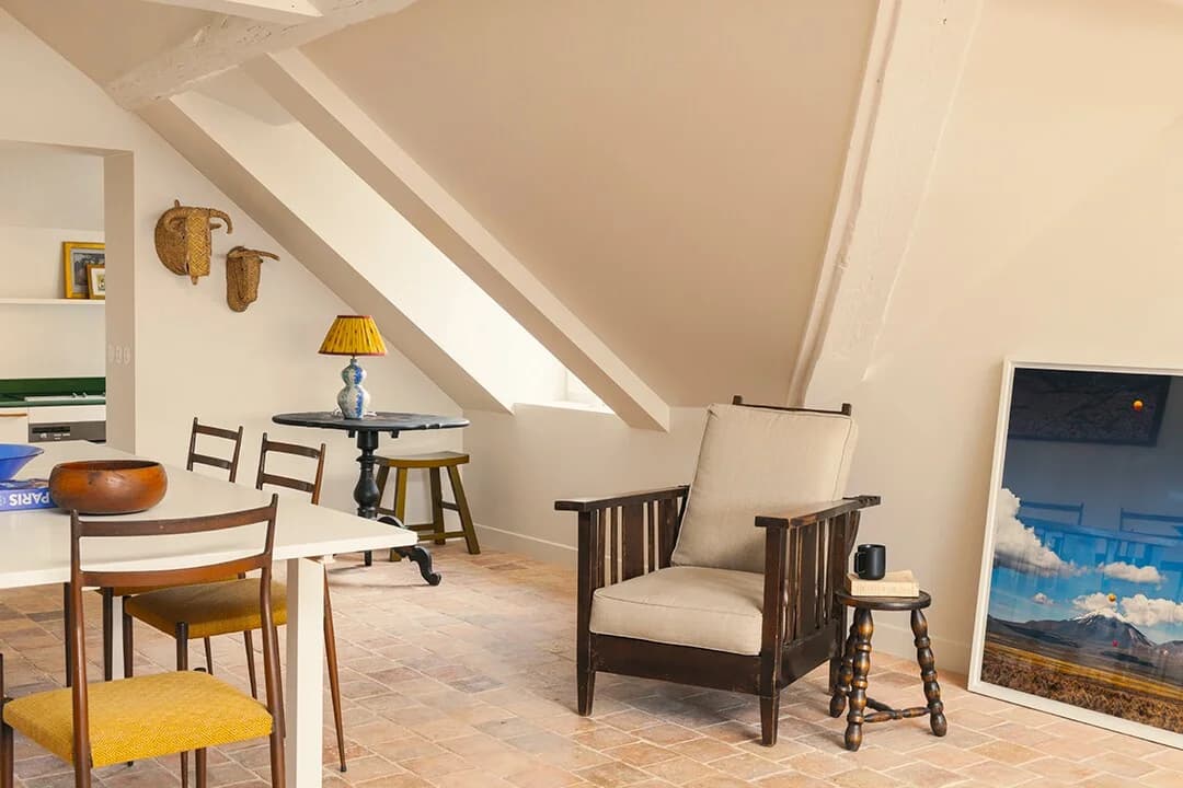 Eaved studio living-dining with terracotta tile floor and yellow lamp