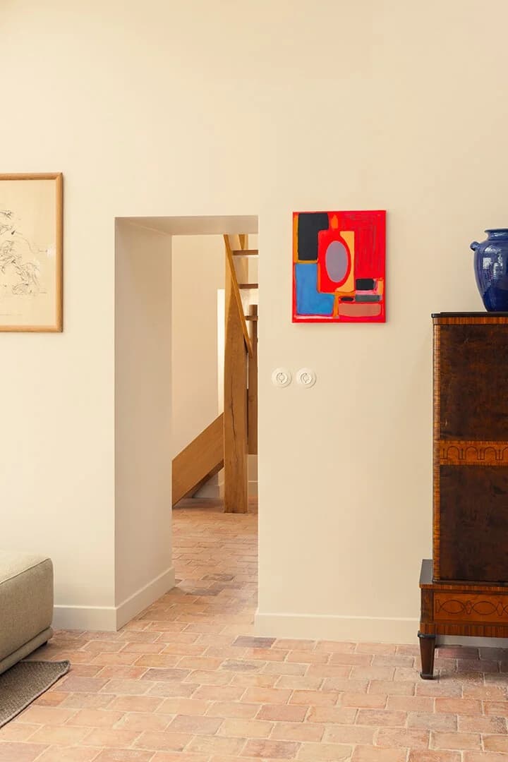Sunlit hallway anchored by abstract painting and burl-wood cabinet