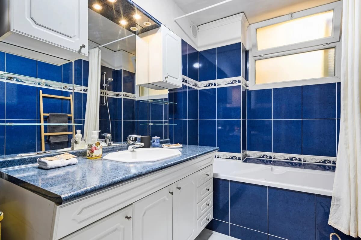 Vintage cobalt-tiled bathroom with stone counter and tub-shower combo