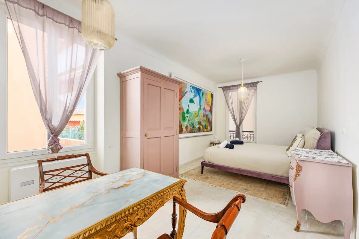 Bedroom with pink armoire, gilt desk and abstract canvas above the bed