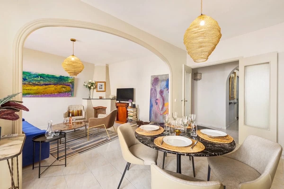 Marble bistro table set for four below woven pendants beside salon arch