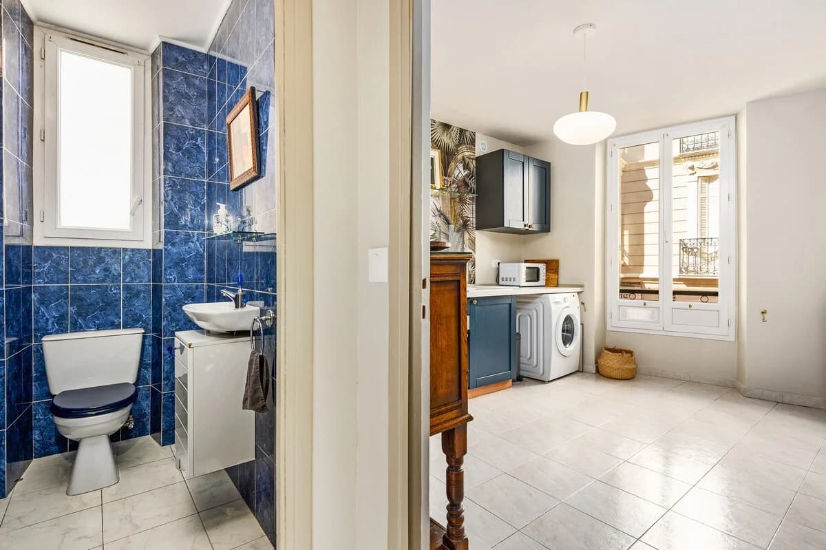 Galley kitchen with white tile floor and tall window onto Belle Epoque facade