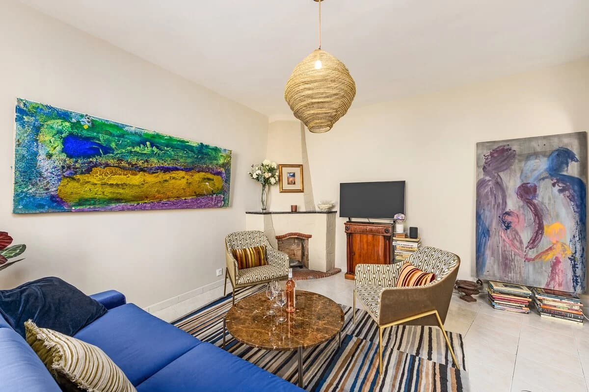 Cosy salon with original fireplace, layered art and striped rug