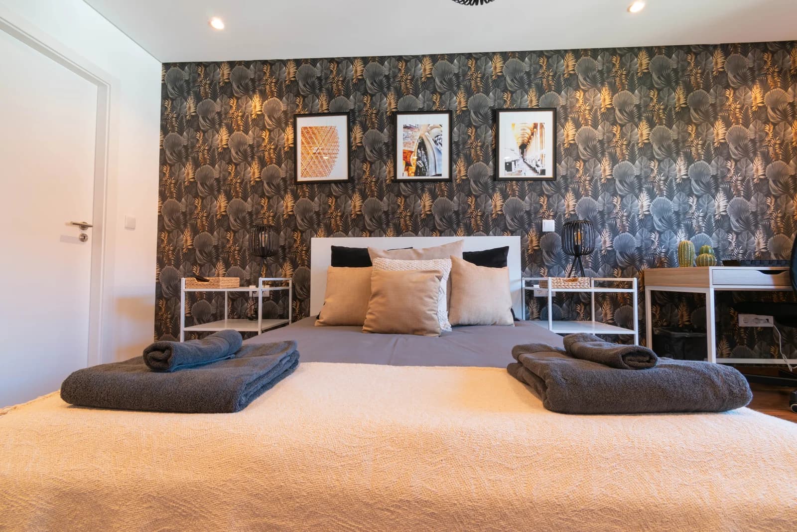 Symmetrical bedroom with botanical wallpaper, twin sconces and triptych