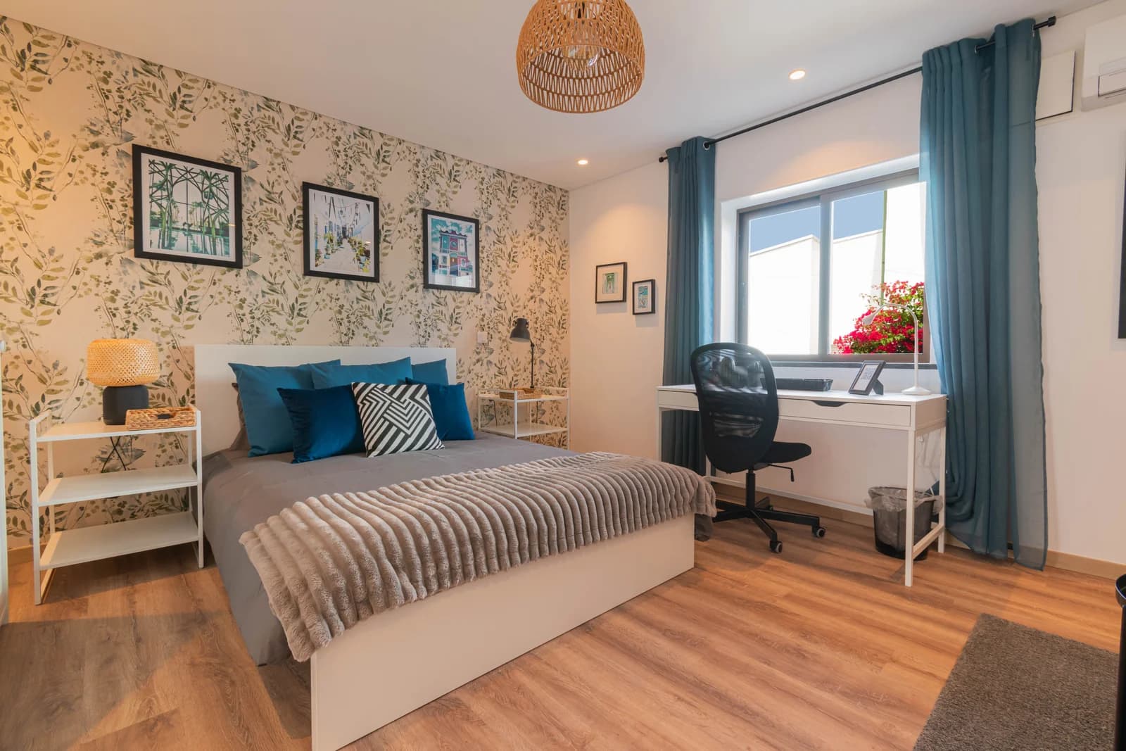 Bedroom with floral wallpaper, teal curtains and tidy desk corner