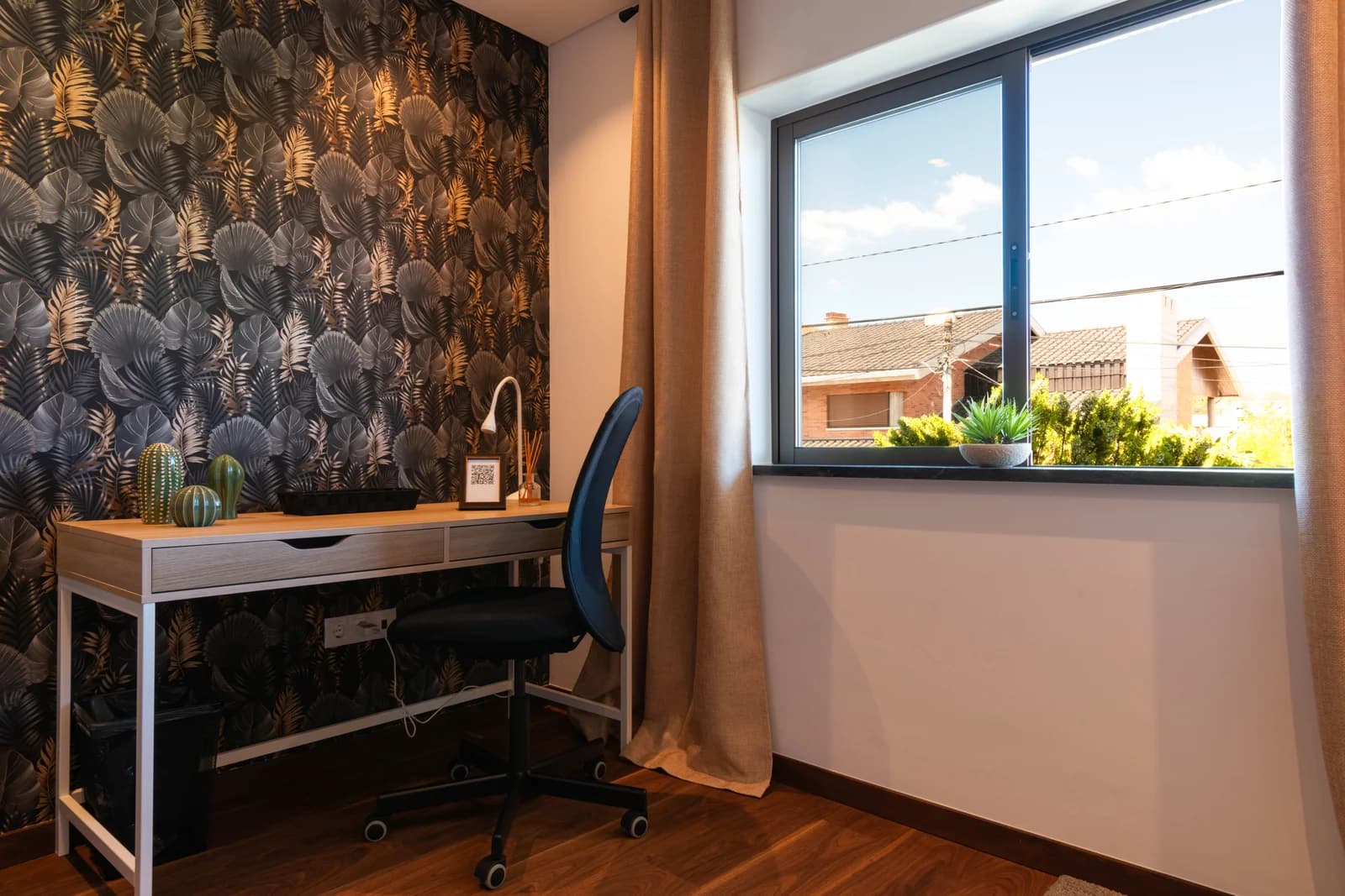 Workspace nook with leafy wallpaper and rooftop view through window