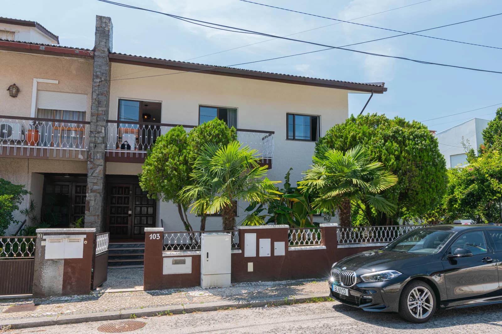 Whitewashed villa facade with palms and small front gate at street level