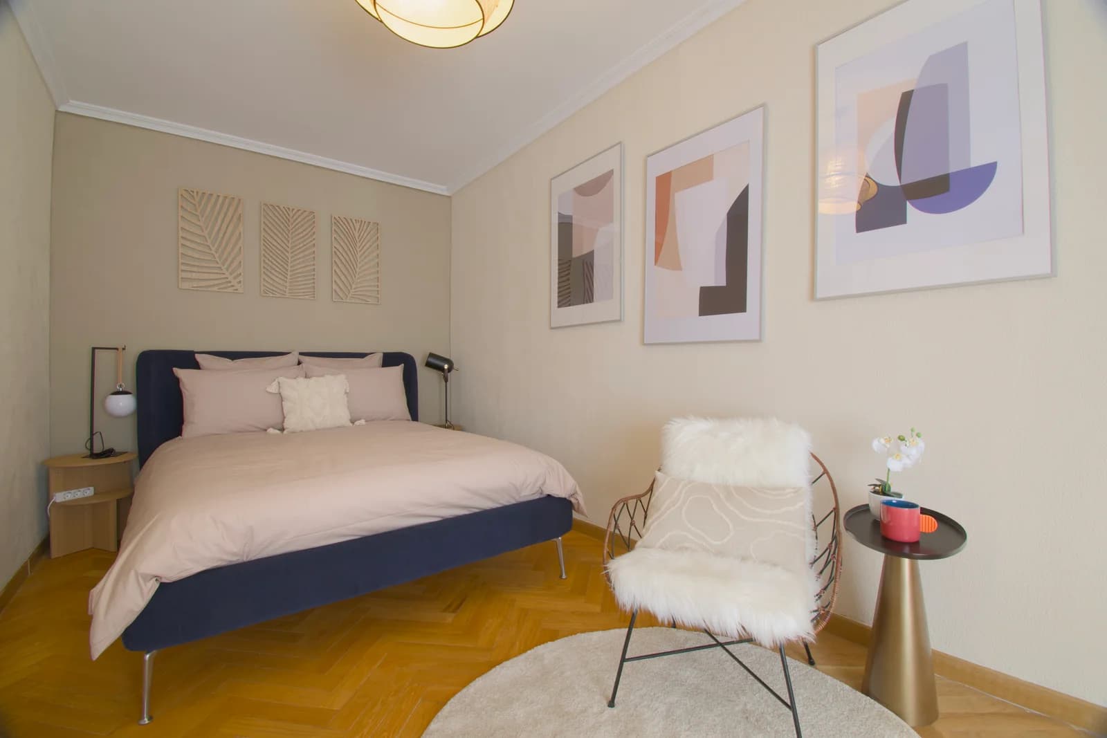 Second bedroom with navy-framed bed and abstract gallery wall