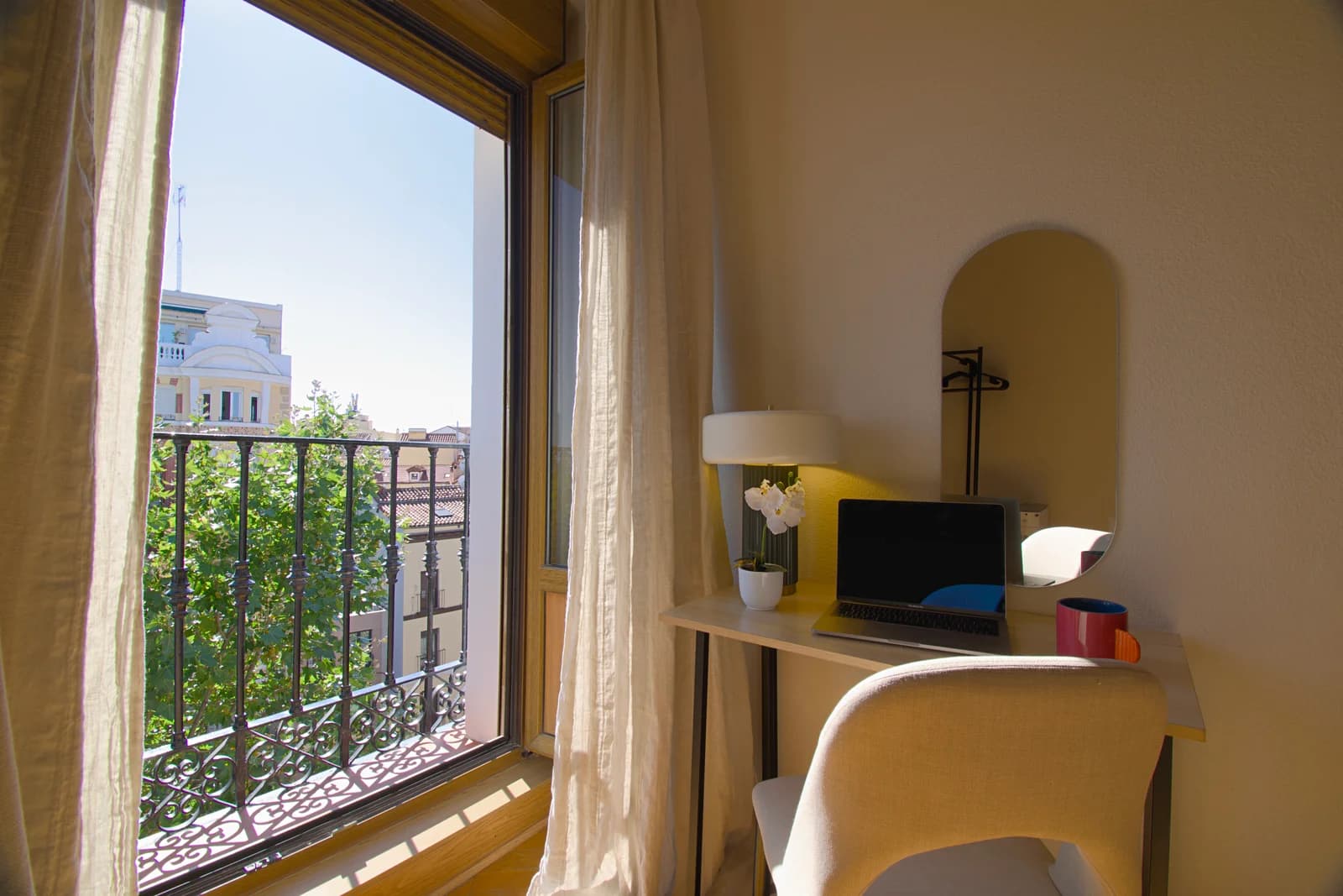 Wrought-iron balcony view over Madrid rooftops from desk corner