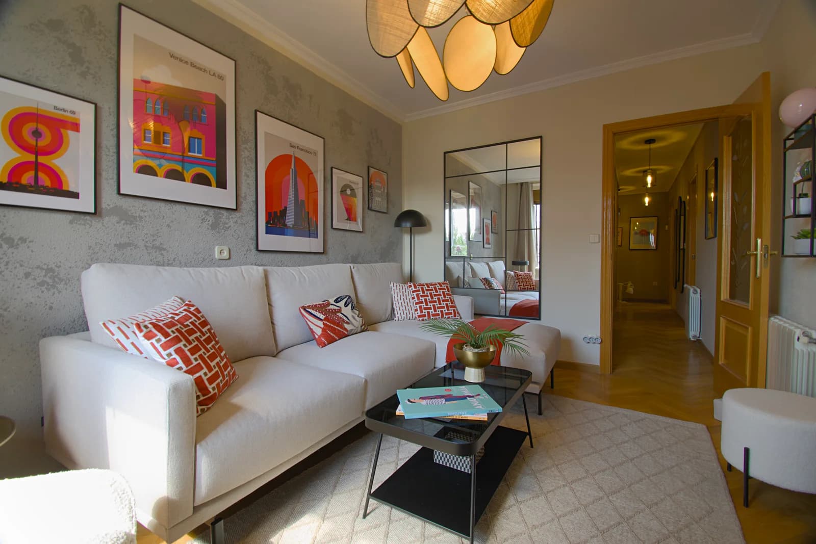 Sectional sofa beneath colorful prints, hallway leading deeper inside