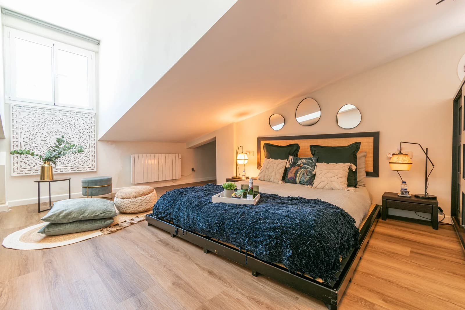 Loft master with platform bed, navy throw, and warm lamp light