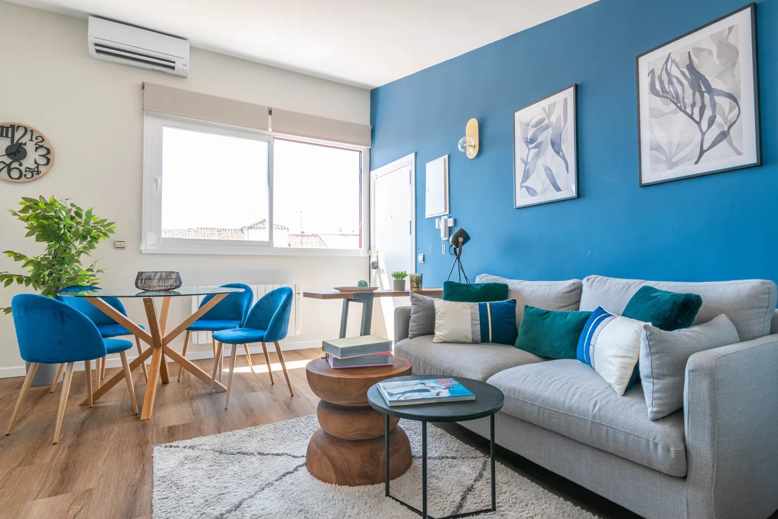 Open-plan living and dining with bold blue accent wall and bright window