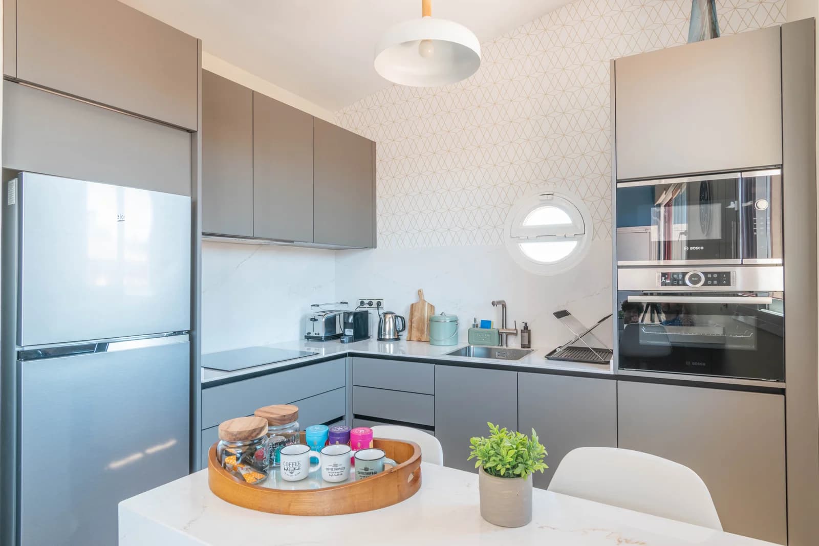 Compact L-shaped kitchen with porthole window and patterned wallpaper