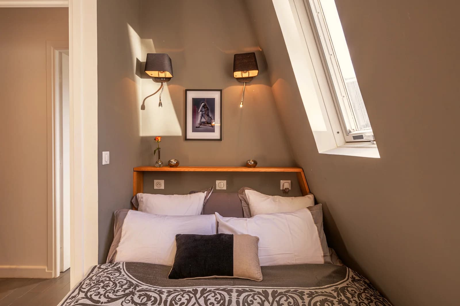 Bedside view with fabric sconces and warm taupe walls