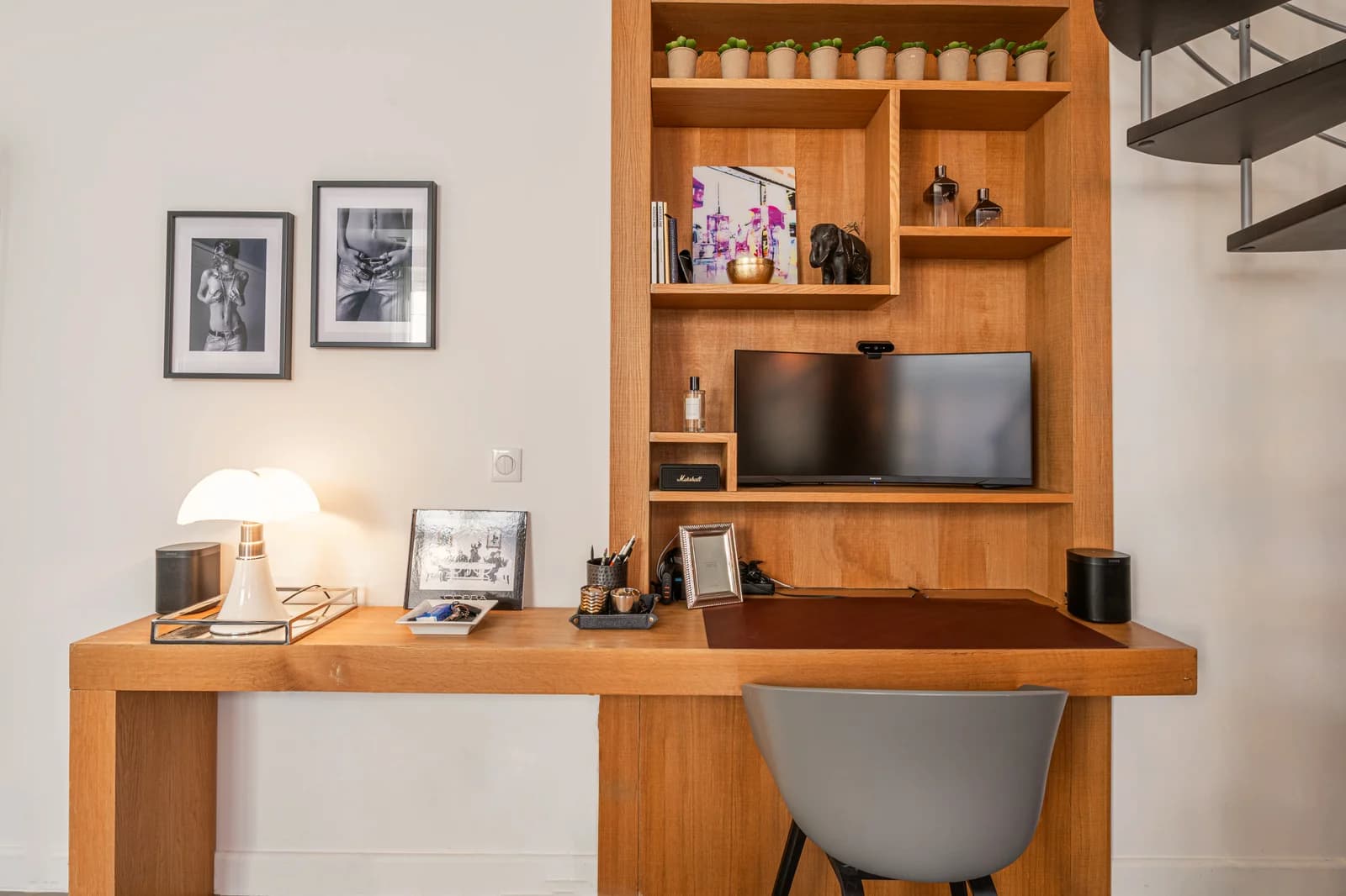Built-in oak desk with framed photographs and pipistrello-style lamp