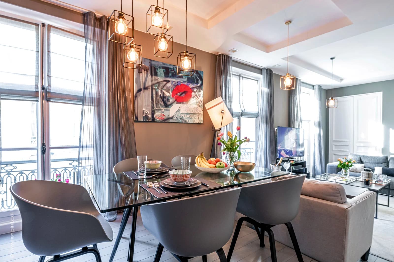 Glass dining table set for six beneath cluster of pendant lights