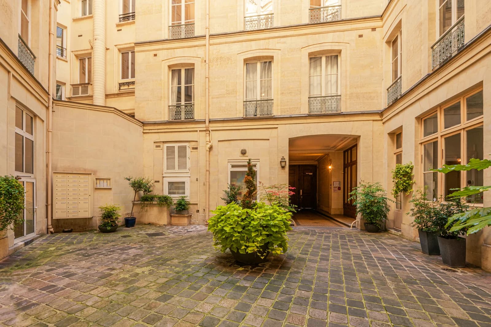 Hausmannian cobblestone courtyard framed by limestone facades