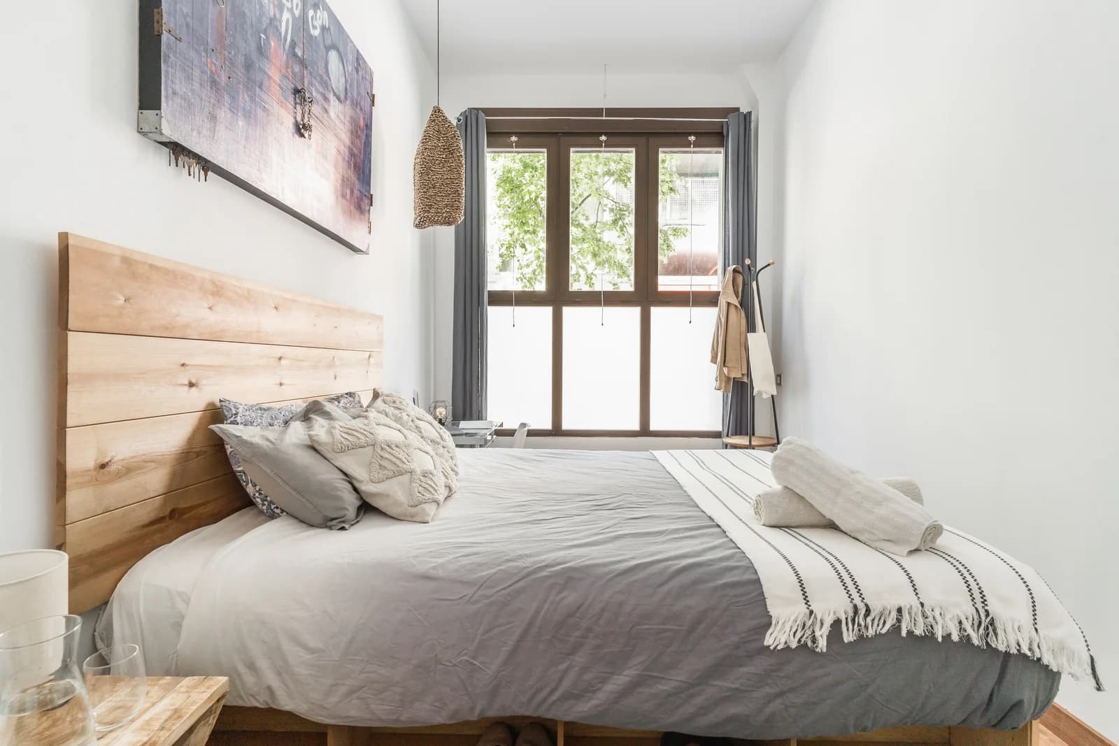 Calm bedroom with timber headboard facing tall window with foliage