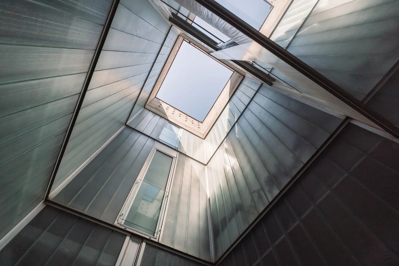 Looking up through atrium glass roof toward open Madrid sky